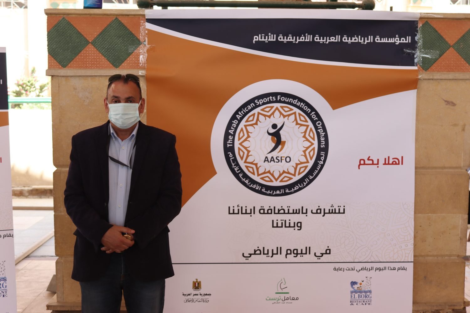 أحد الضيوف أمام لافتة الفعالية